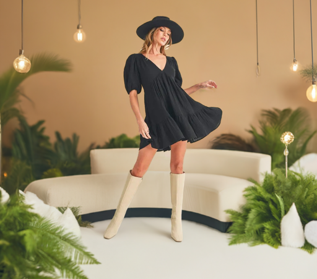 This short sleeve black mini dress features a charming tied back detail and playful ruffled accents.